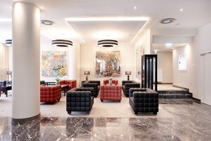Um hall de entrada com assentos confortáveis, uma obra de arte grande e piso de mármore.