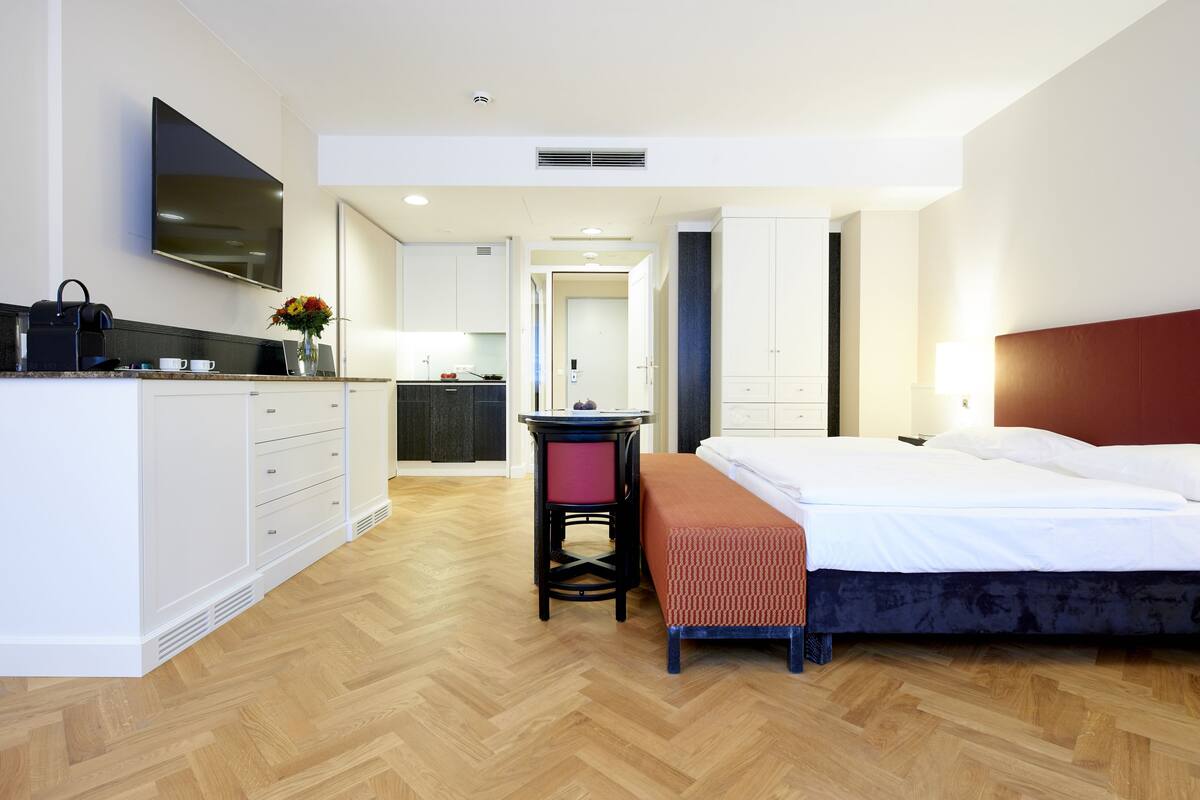Ein Hotelzimmer mit Bett, Schreibtisch, Fernseher und Bad.