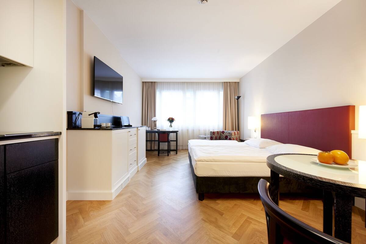 Ein Hotelzimmer mit Bett, Schreibtisch, Fernseher und Esstisch.