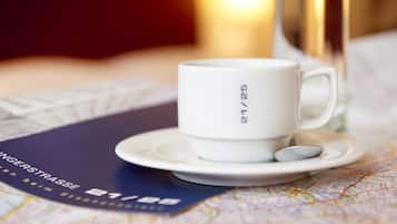 A white mug with "21/25" on a saucer, placed on a table with a map and a booklet.