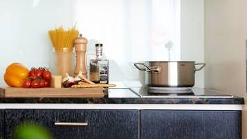 Una encimera de cocina con una olla, pasta, tomates, ajo y un molinillo de pimienta.