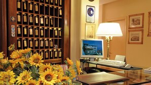 A hotel room with a desk, computer, lamp, and a wall of keycards. - Titano Suites (San Marino)