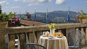 A terrace with a table set for breakfast, overlooking a mountainous landscape. - Titano Suites (San Marino)