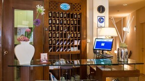 A reception desk with a glass top, a computer monitor, a lamp, and a decorative vase. - Titano Suites (San Marino)