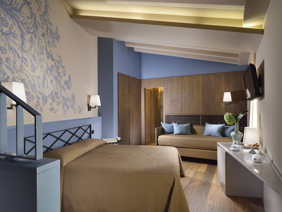 Habitación de hotel con una cama grande, un sofá, un escritorio y un televisor de pantalla plana, además de un televisor montado en la pared.