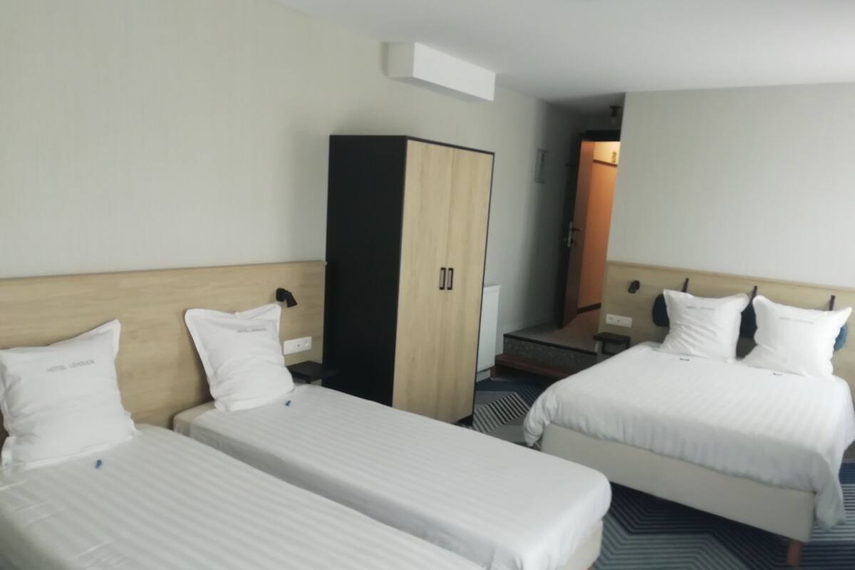 Ein Hotelzimmer mit zwei Einzelbetten, einem Kleiderschrank und einem kleinen Schreibtisch.