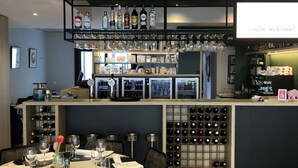 Uma área de bar moderna, com adega, balcão e um letreiro acolhedor.