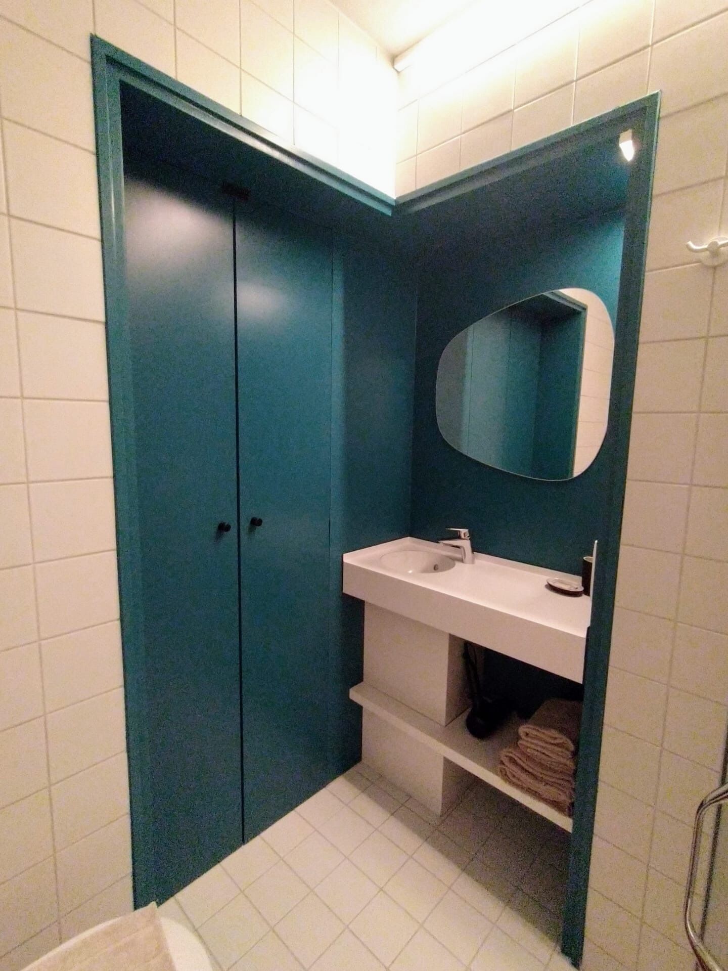 Une salle de bain avec un lavabo blanc, un miroir et un meuble bleu.