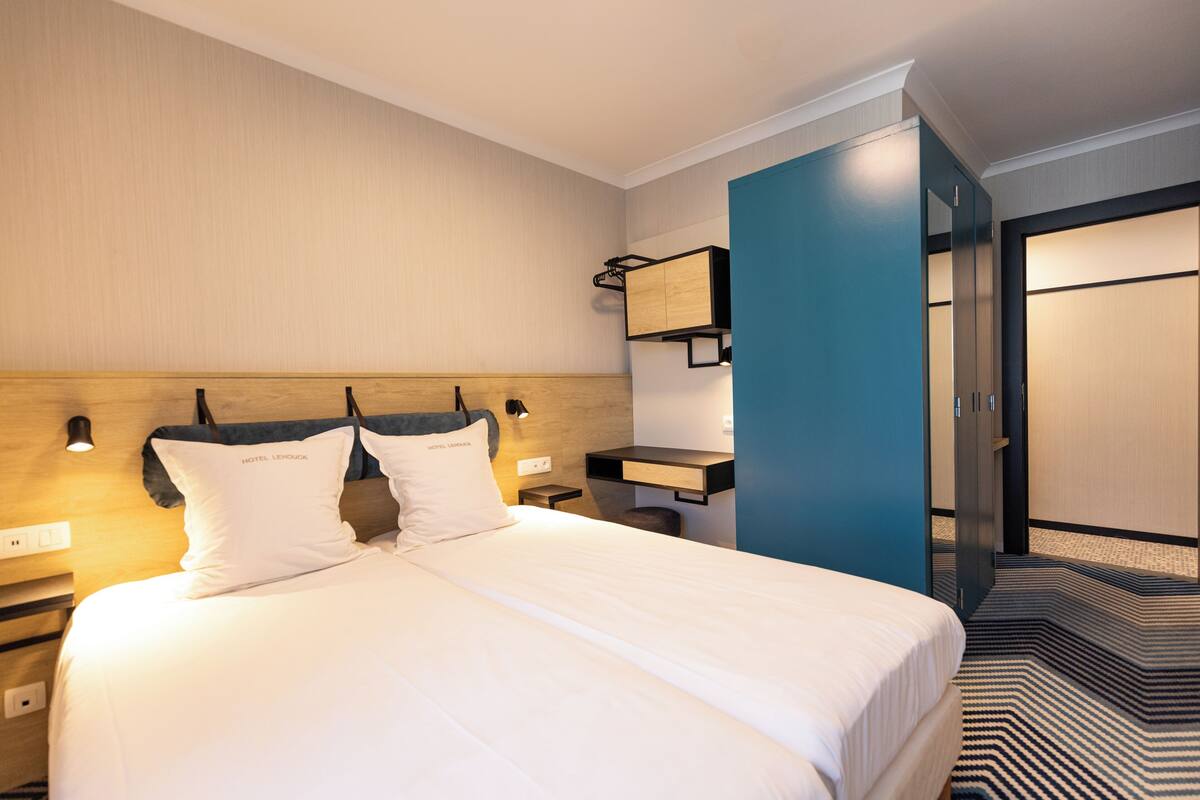 Ein Hotelzimmer mit einem großen Bett, einem Nachttisch, einem Schreibtisch und einem Kleiderschrank.