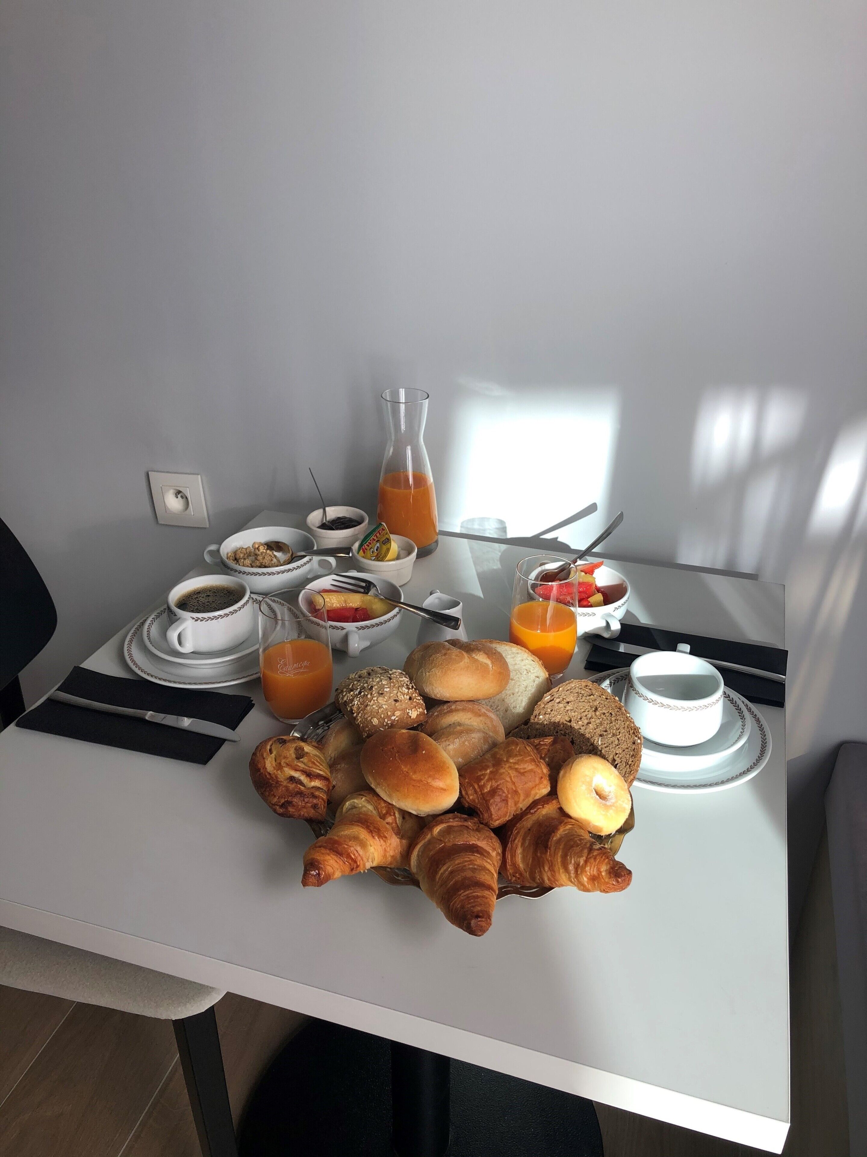 A breakfast table with croissants, bread, and juice.