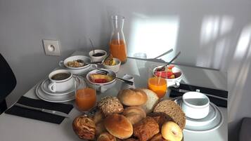 A breakfast table with croissants, bread, and juice.