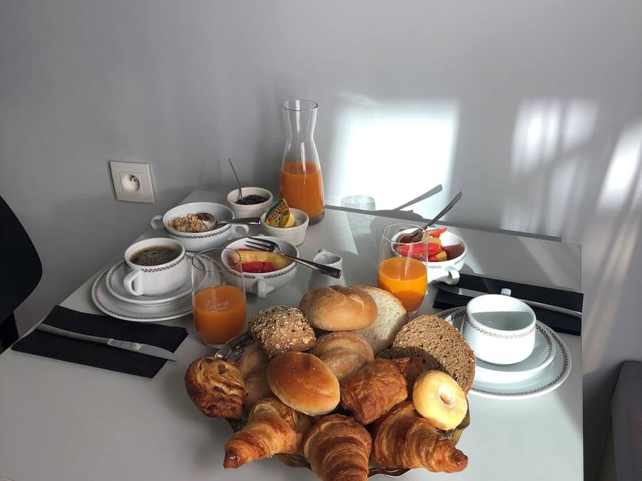 A breakfast table with croissants, bread, and juice.
