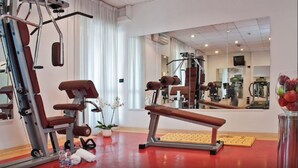 Een sportschool met trainingsapparatuur, een spiegel en een potplant.