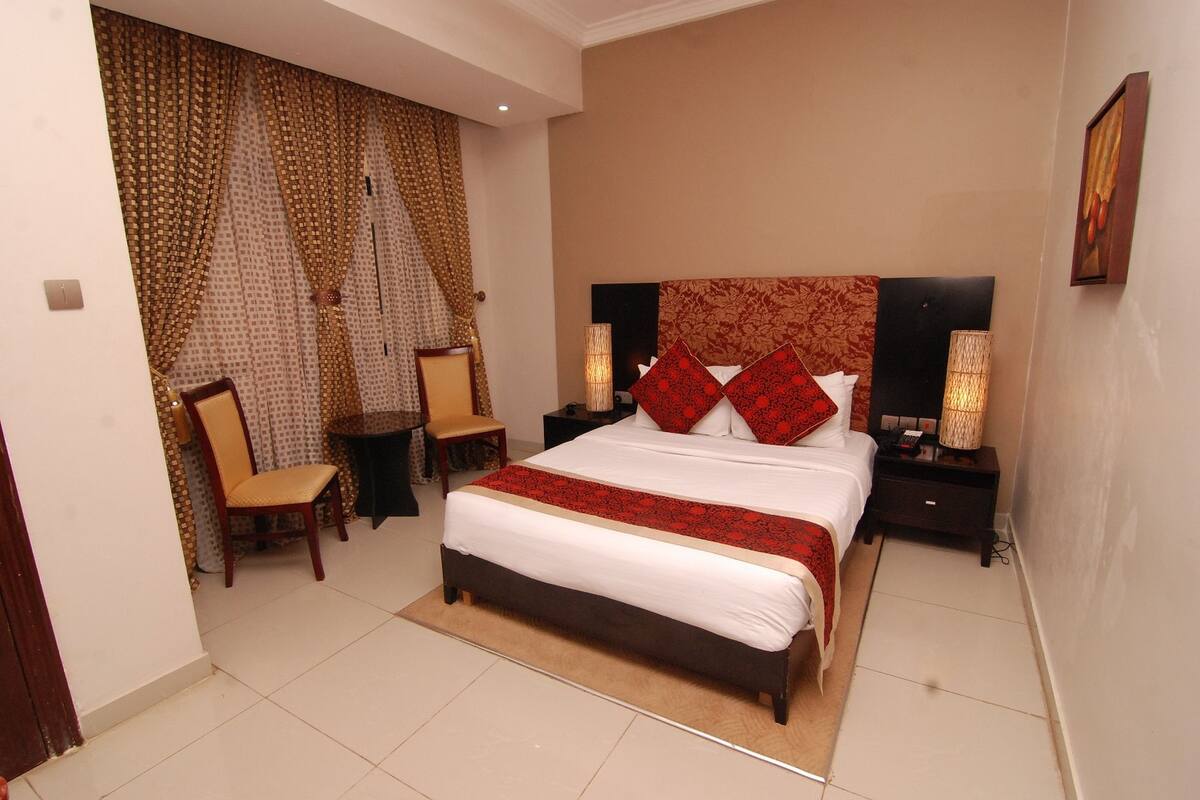 A bedroom with a large bed, two bedside tables, a chair, and a small table.