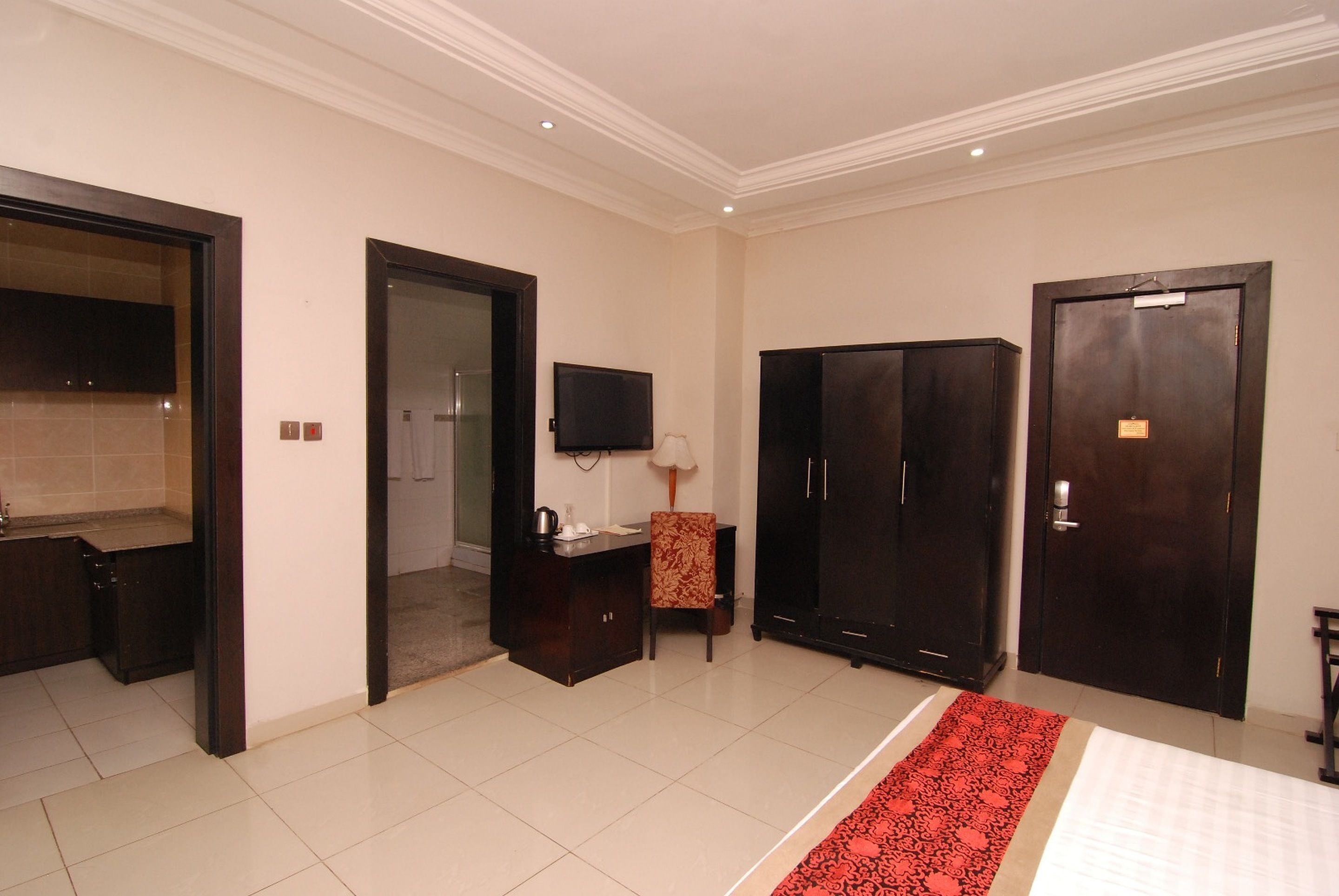 A hotel room with a bed, a desk, a chair, a TV, and two wardrobes.
