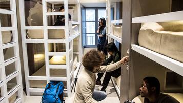 Una habitación compartida con literas, una mochila azul y un par de zapatillas en el suelo.