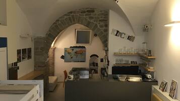 Habitación de hotel pequeña con cama, escritorio y kitchenette.