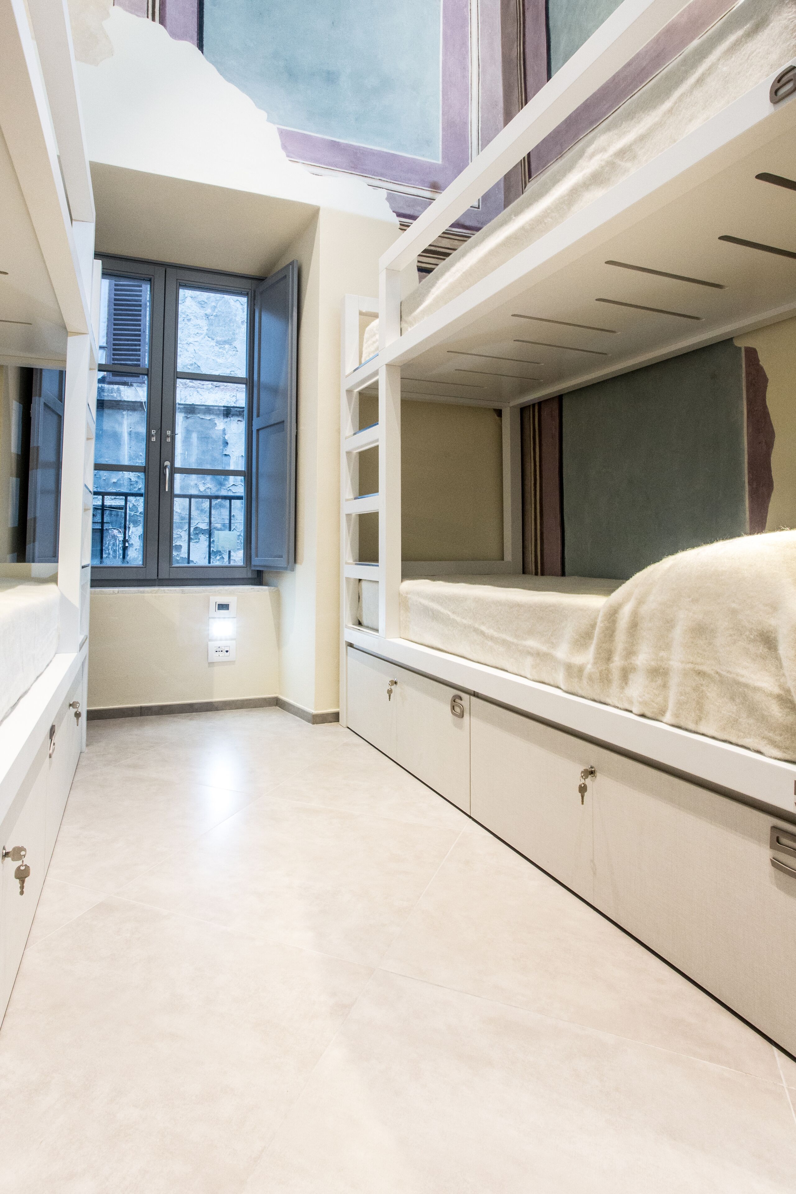 A room with bunk beds, a window, and a built-in desk.