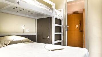 Ein Hotelzimmer mit Etagenbett, Nachttisch, Kleiderschrank und Duschbereich.