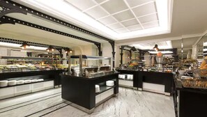 A spacious food court with multiple counters and seating areas, featuring a modern design with black and white color scheme. - Metropolitan Hotels Taksim (Istanbul)