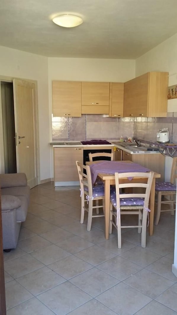 A compact kitchen with wooden cabinets, a dining table with chairs, and a small countertop.