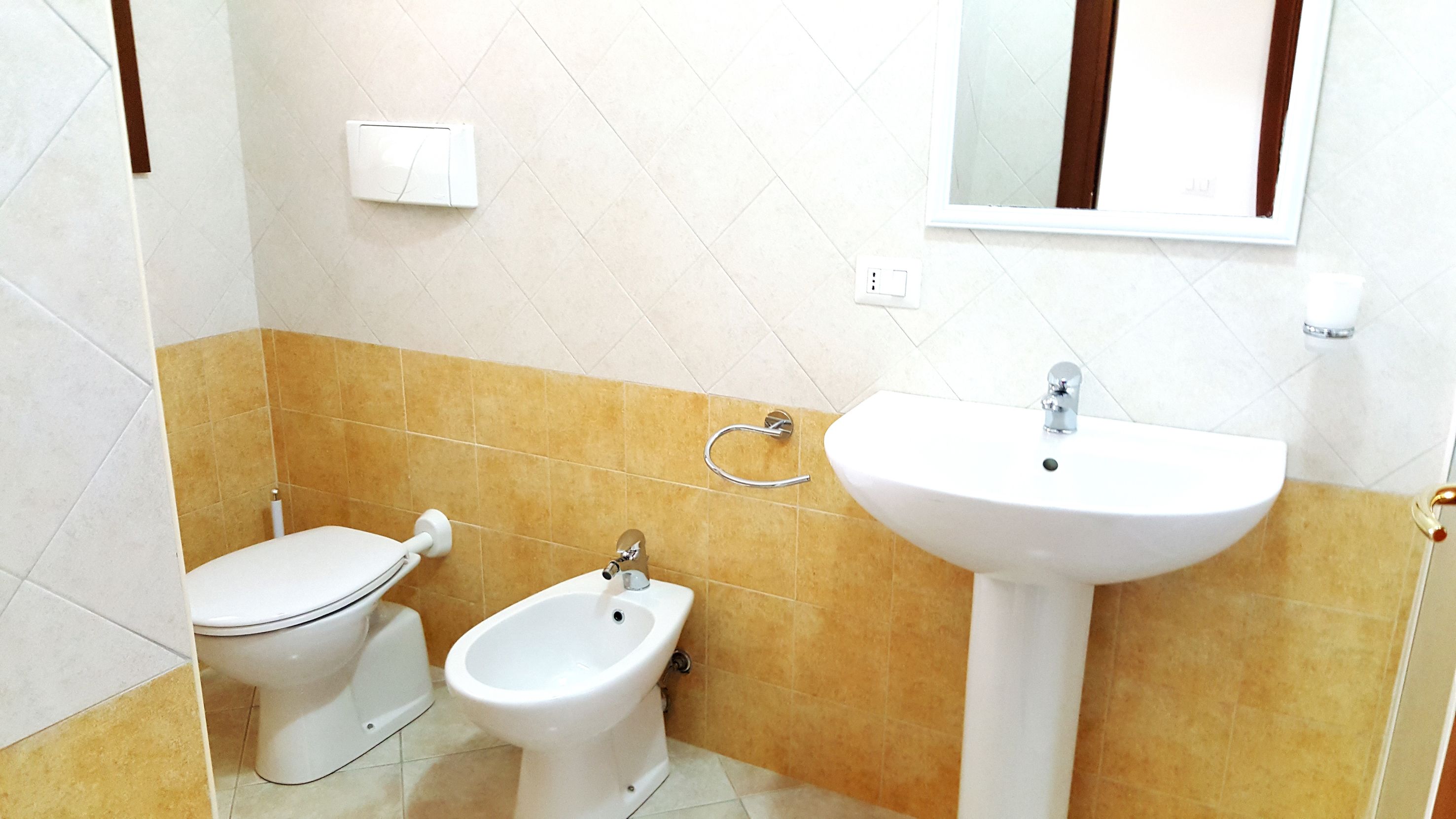 Een badkamer met toilet, bidet en wastafel.