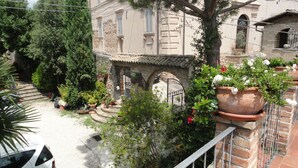 A courtyard with a stone staircase leading to a door, surrounded by potted plants and a tree. - La Terrazza di spello (Spello)
