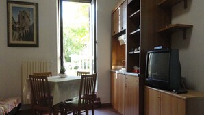 A compact living space with a dining area, a kitchen with wooden cabinets, and a television. - La Terrazza di spello (Spello)