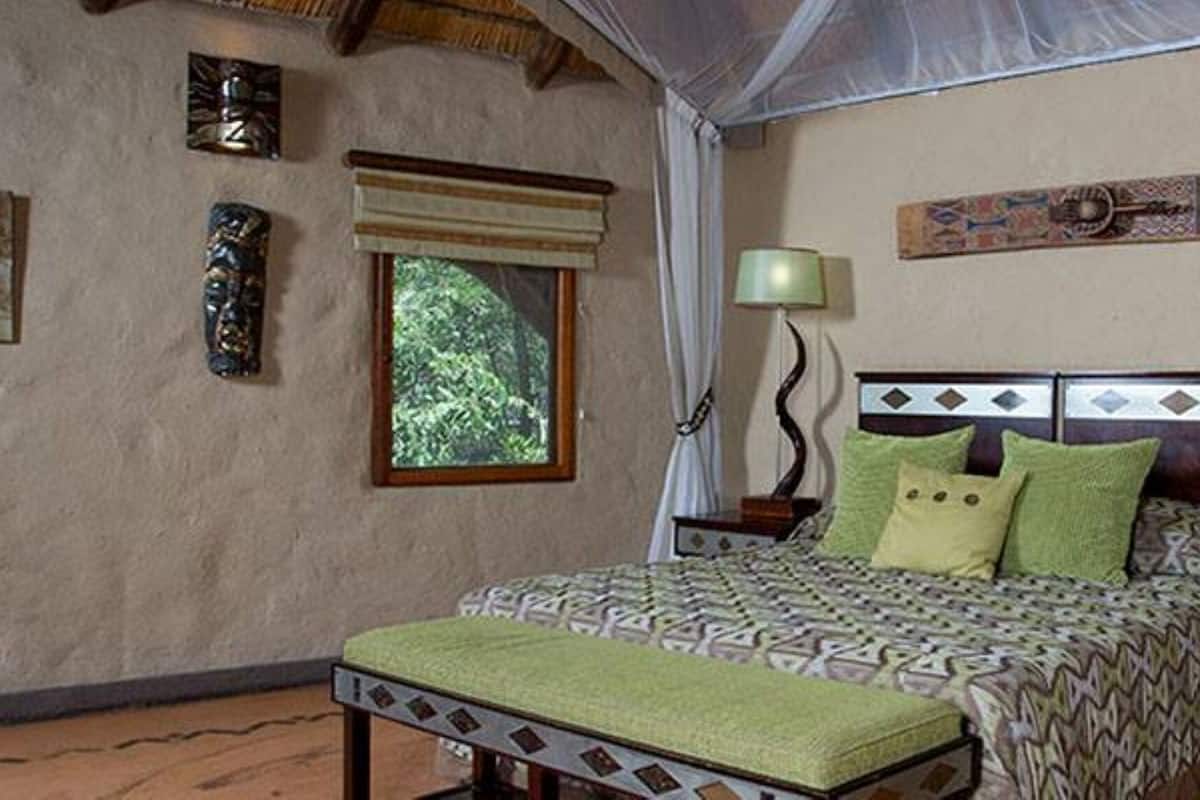 Une chambre à coucher comprenant un lit, deux tables de chevet, une fenêtre et une œuvre d’art accrochée au mur.