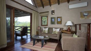 Una sala de estar acogedora con terraza de madera, un sofá, un sillón, una mesa de centro y una lámpara.