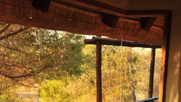 A spa area with a large hot tub, a wooden deck, and a view of a natural landscape. - Lukimbi Safari Lodge (Nkomazi)