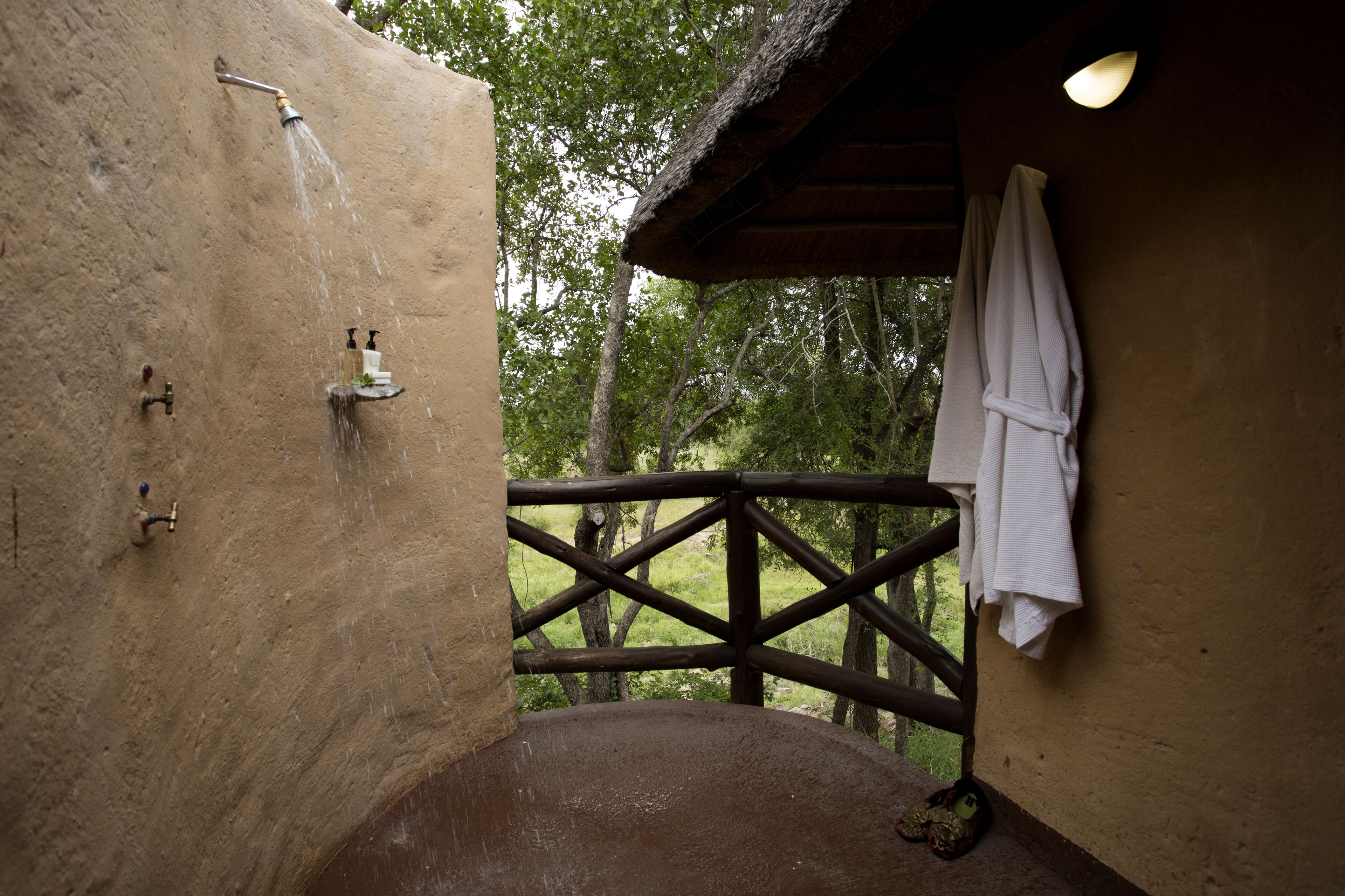 Ein rustikales Badezimmer mit Holzbalkon, Dusche und einem Handtuch an der Wand.