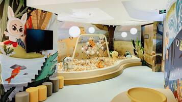 Children can play and relax in a safe, engaging space with a colorful mural, play structure, and soft seating.