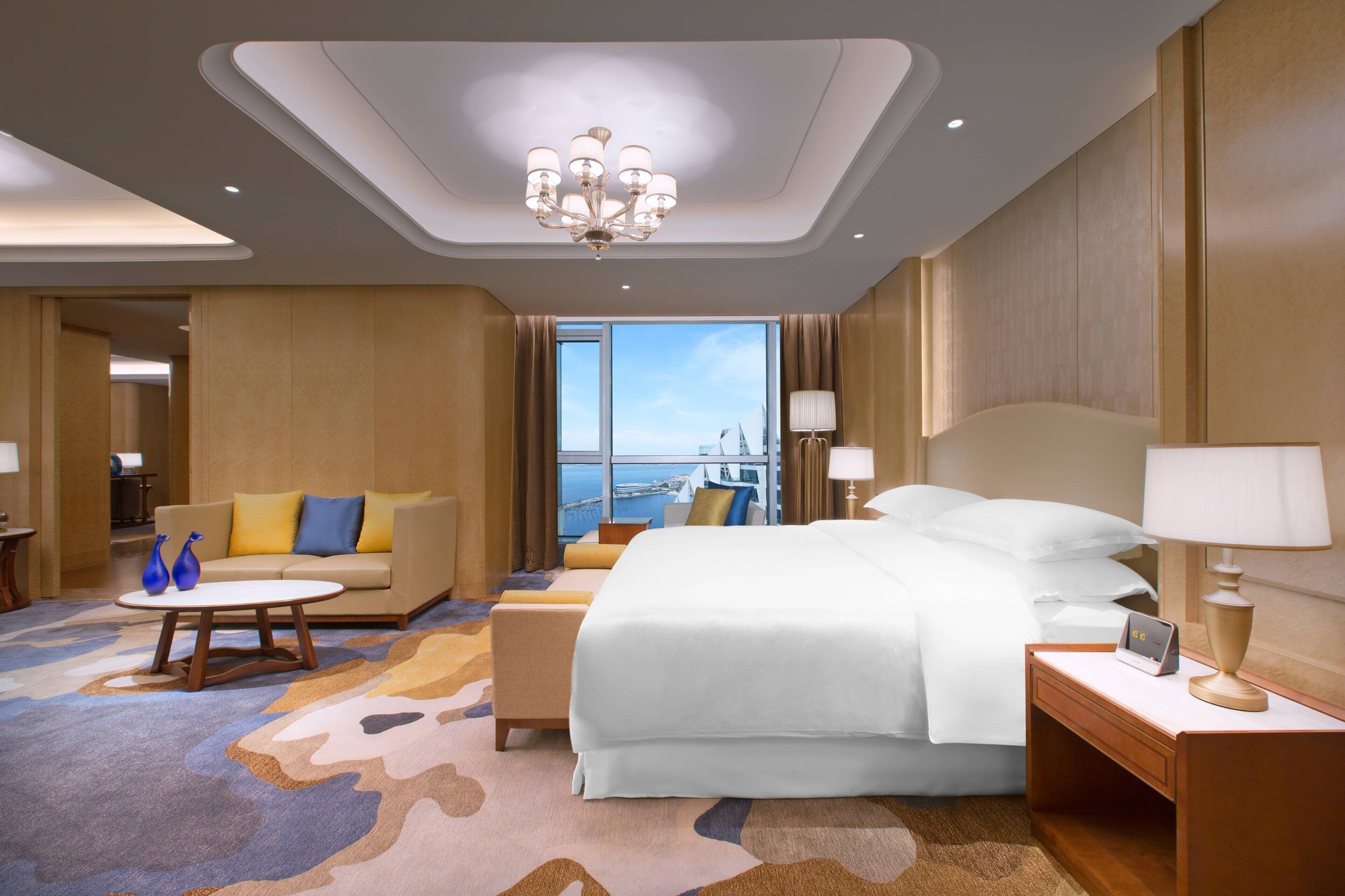 Habitación de hotel con una cama grande, un sofá, una mesa de centro y vistas a la ciudad.