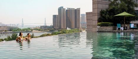A swimming pool with a view of high-rise buildings and a bridge in the background.