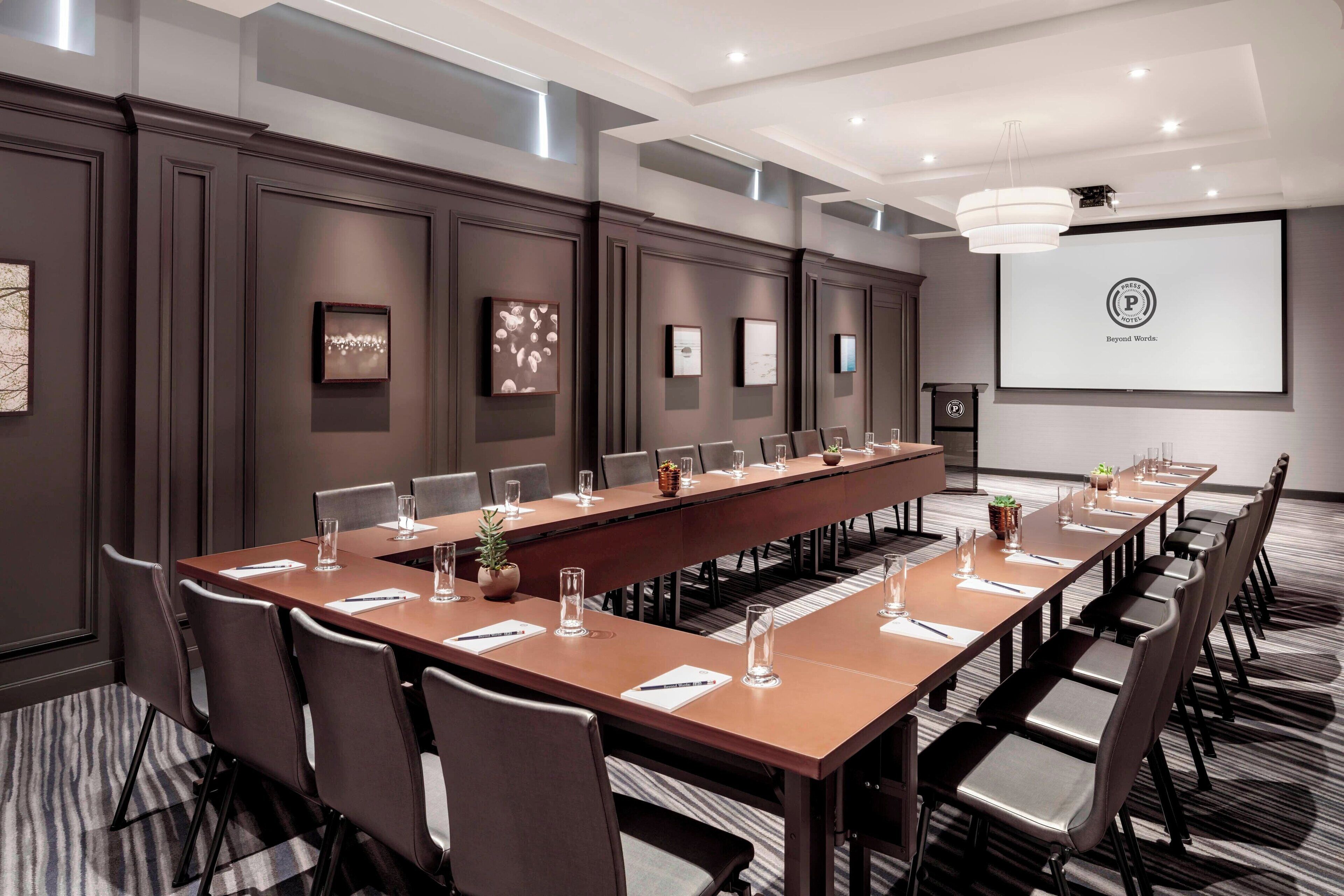 A conference room with a long table, chairs, and a projector screen.