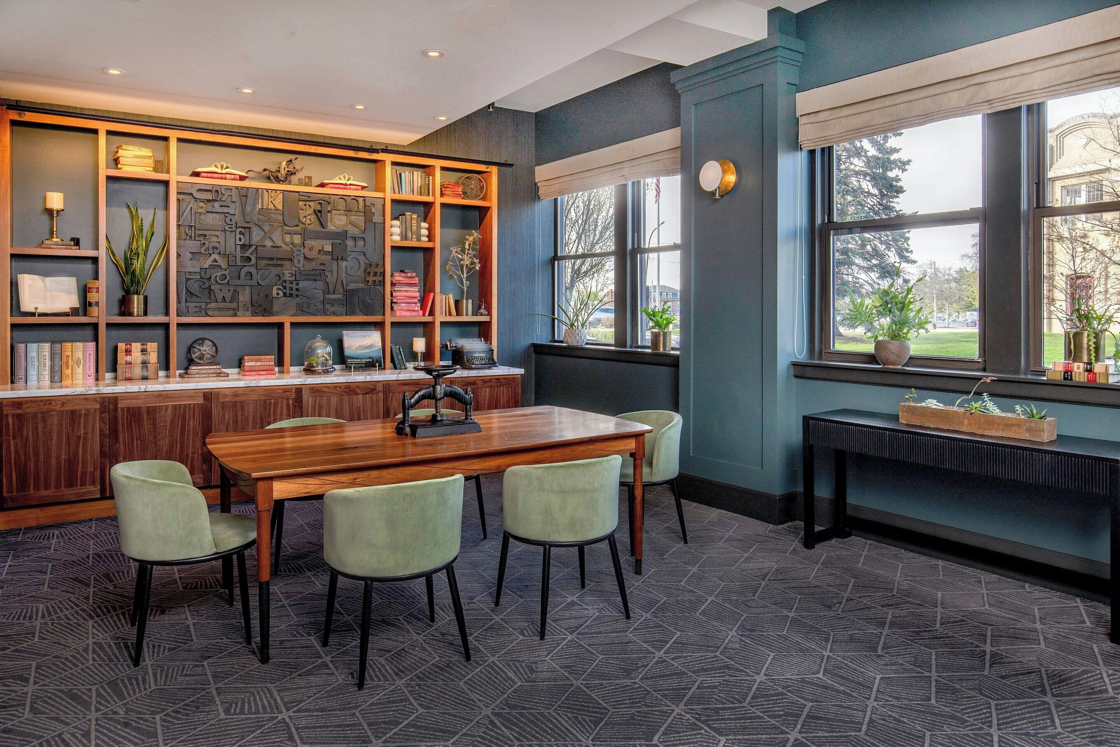 Una cocina moderna con una mesa y sillas de madera, una estantería empotrada y un ventanal con vistas al exterior.