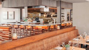 A modern restaurant with a bar area, wooden tables, and leather booths. - The Press Hotel, Marriott Autograph Collection (Portland)