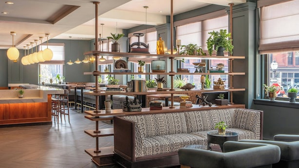 A modern interior with a bar area, seating, and shelves with plants and books. - The Press Hotel, Marriott Autograph Collection (Portland)