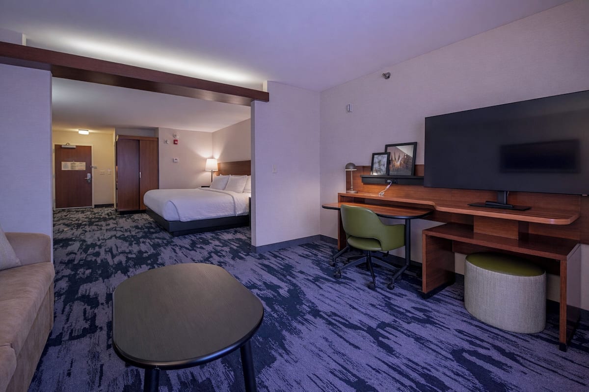 A hotel room with a bed, desk, television, and a small seating area.