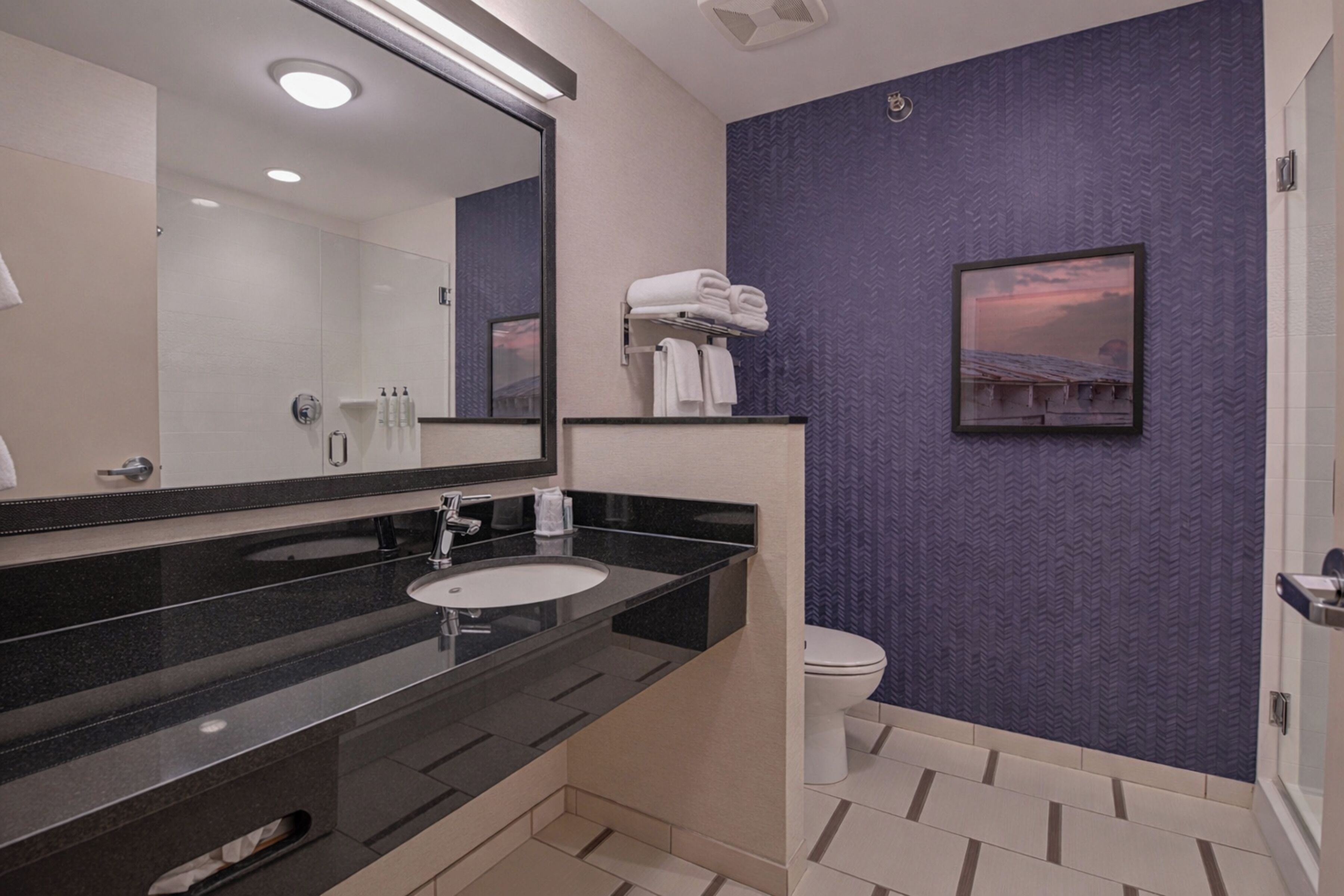 A modern bathroom with a large mirror, a sink, a toilet, and a shower area.
