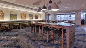 Un vestíbulo moderno de hotel con una zona de bar, asientos y obras de arte en las paredes.