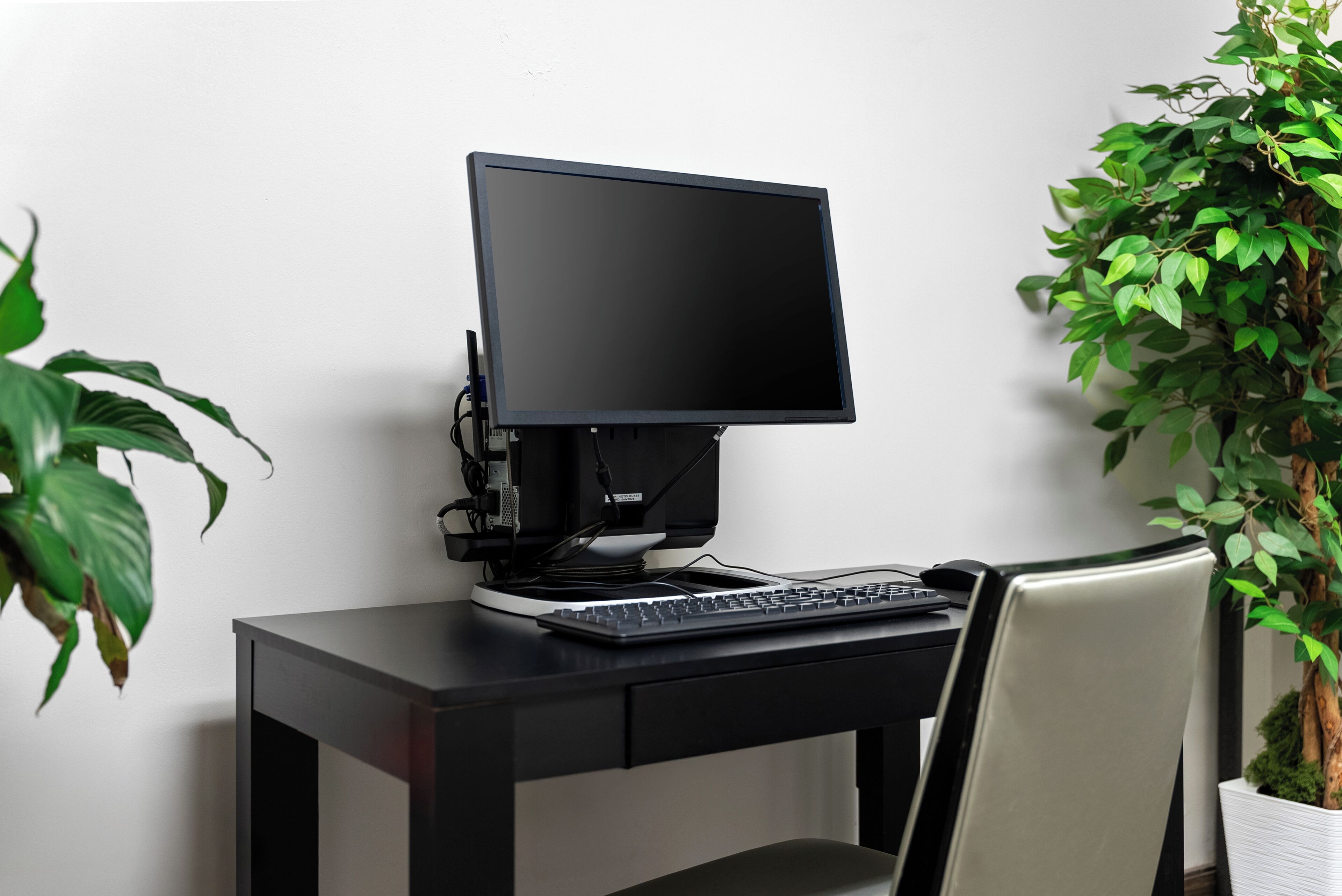 A computer desk with a monitor, keyboard, and chair.