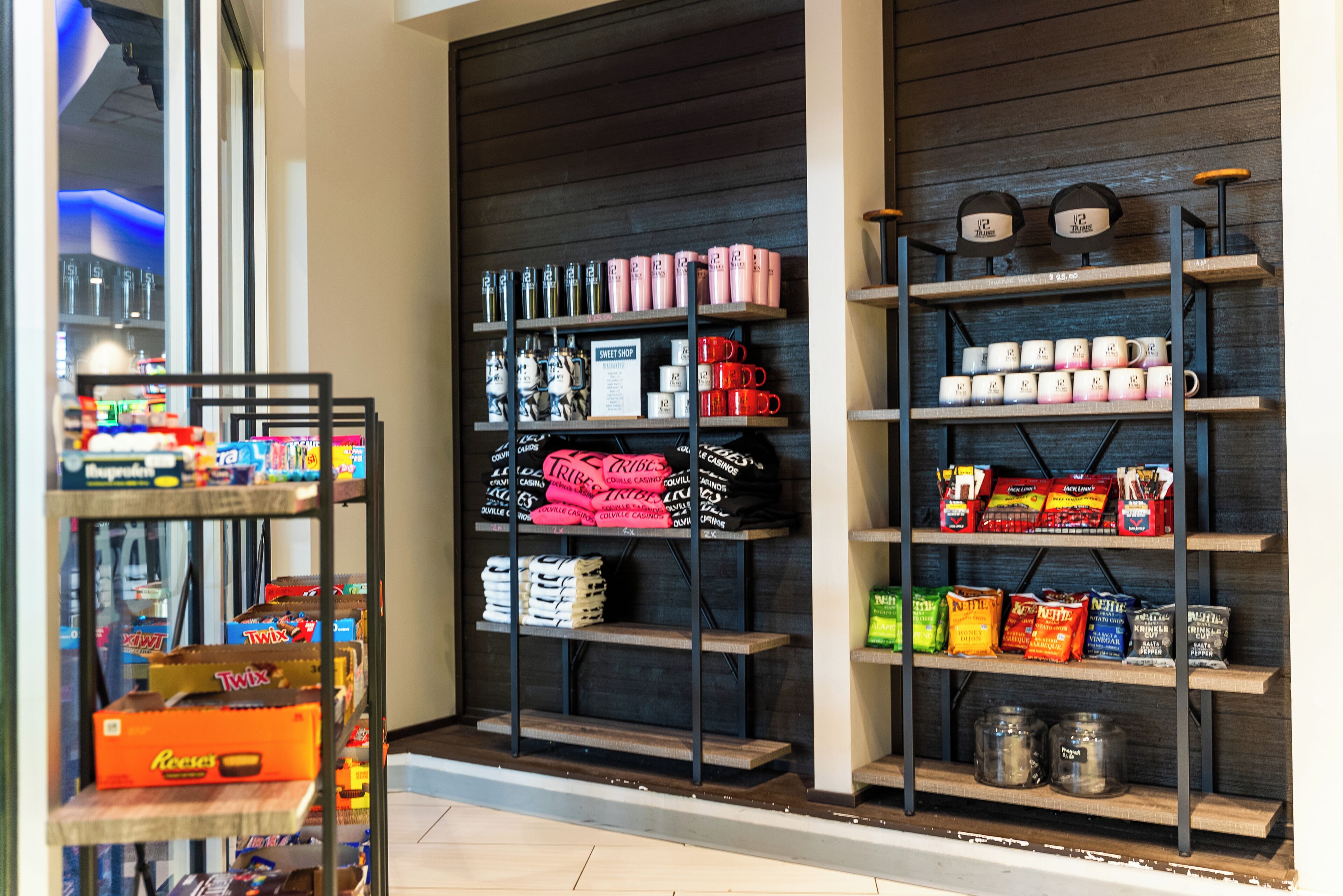 Interior de una tienda con estantes llenos de diversos productos, como aperitivos, tazas y productos envasados.