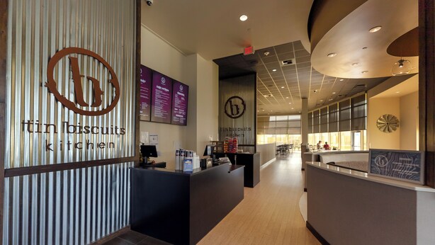 Un espace cuisine moderne avec un comptoir, un tableau affichant le menu et une enseigne indiquant « Cuisine de biscuits en conserve ».