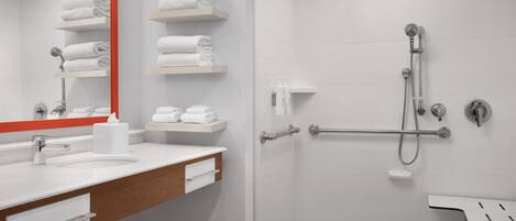 Un baño moderno con lavamanos, espejo y toalleros blancos.