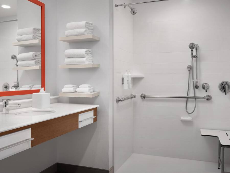 Une salle de bain moderne avec un lavabo blanc, un miroir et des porte-serviettes.