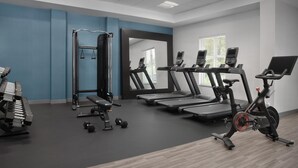 Un gimnasio moderno con cintas de correr, bicicletas estáticas y pesas libres.