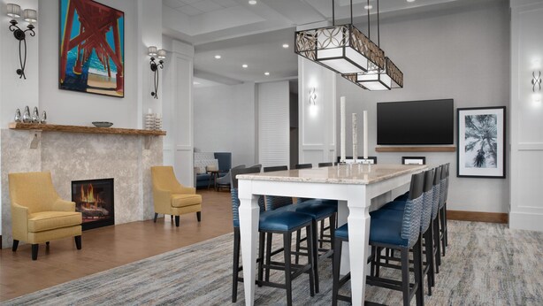 Una sala de estar moderna con chimenea, un comedor con taburetes de bar y un televisor grande montado en la pared.