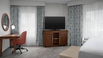 Een hotelkamer met een houten bureau, een televisie, een bed en een stoel.